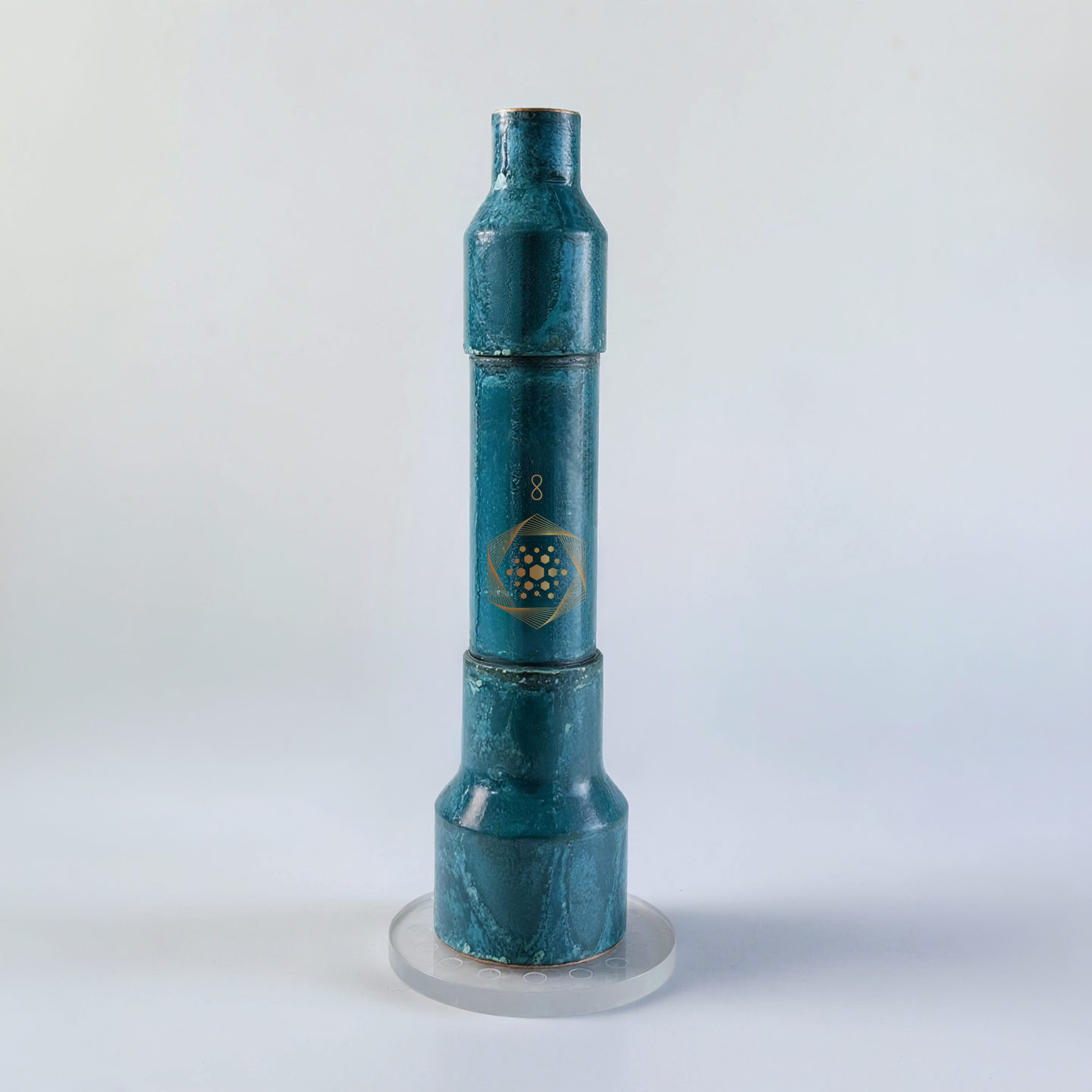 The Aqua Energizer Care Kit by The Wellness Enterprise features a blue, cylindrical structured water device with a hexagonal symbol and the number 8, standing upright on a round, clear crystal stand against a plain background.