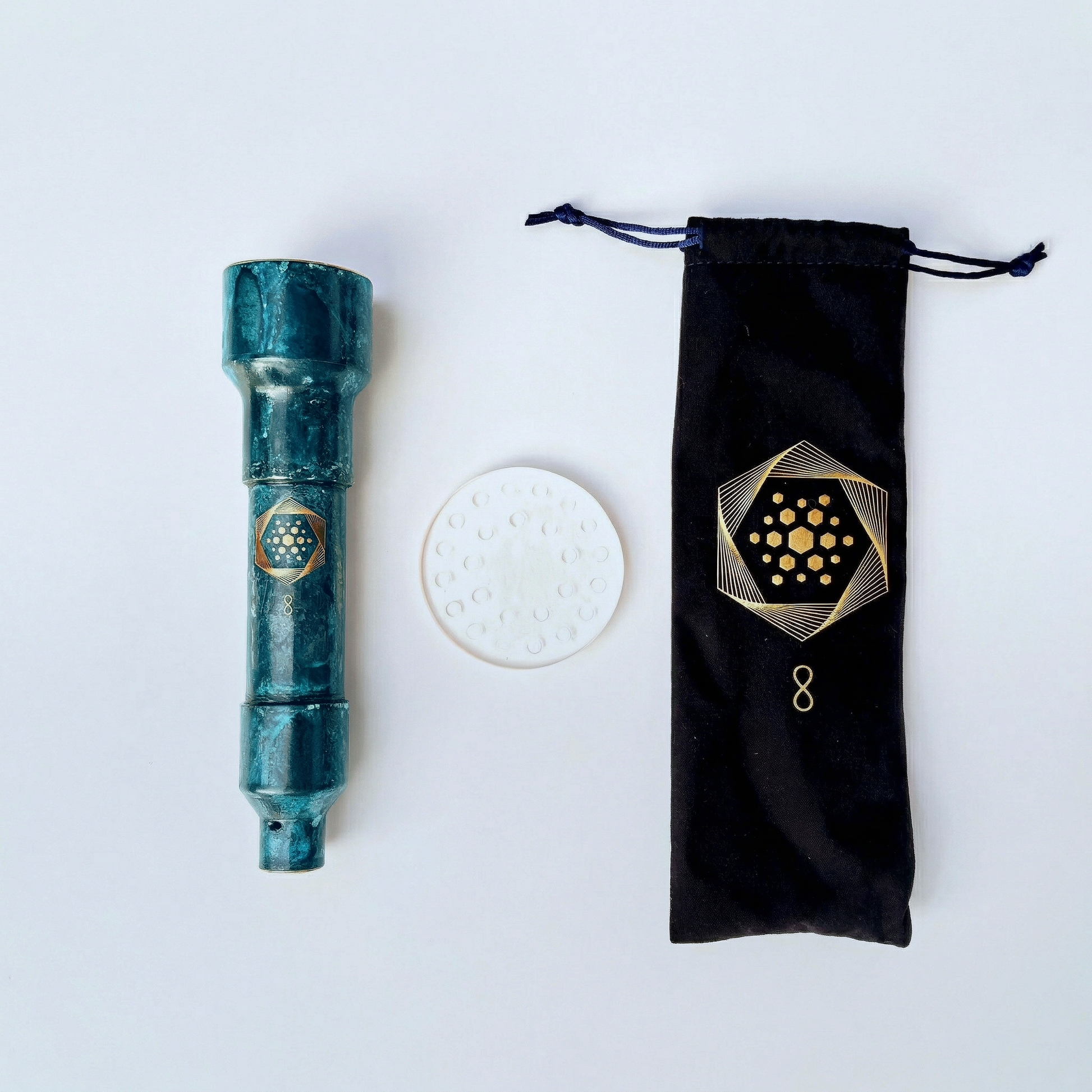 An Aqua Energizer On-the-Go Structured Water Device from Aqua Energizer (teal cylinder), a round white disc, and a black drawstring pouch with a gold geometric design are arranged on a white surface.