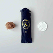The Aqua Energizer Care Kit by The Wellness Enterprise features a brown textured item, a black drawstring pouch with a gold geometric pattern, and a crystal clearing stand arranged side by side on a light surface.