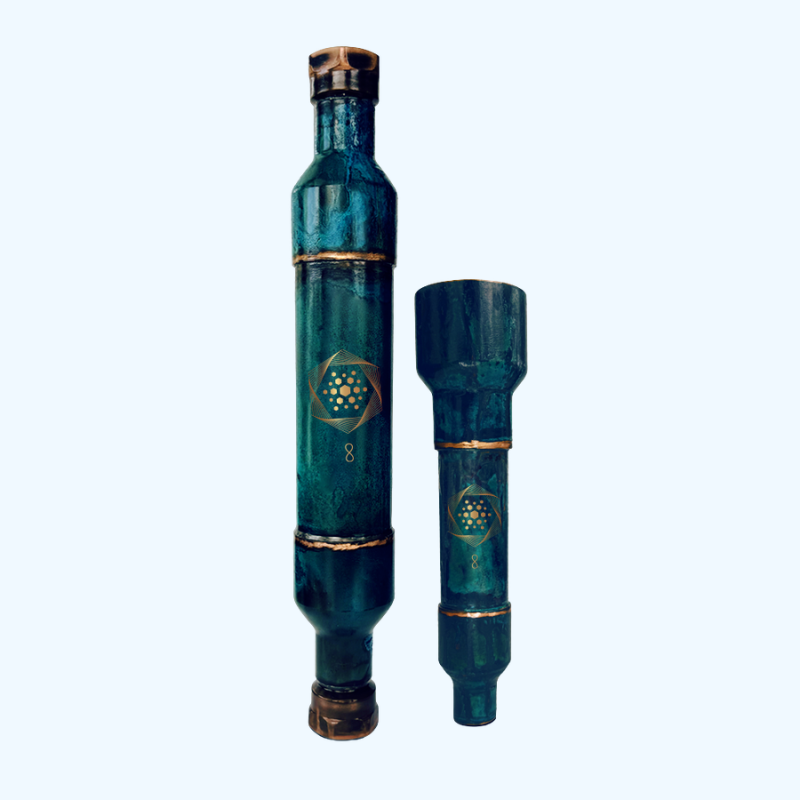Two cylindrical, teal-colored metal devices with gold accents and geometric patterns stand upright against a plain light background—The Wellness Enterprise’s Whole House Aqua Energizer + FREE Aqua Energizer On-the-Go are structured water solutions designed to enhance hydration and promote natural energy as part of your daily routine.